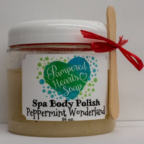 Clear 16 ounce container with white lid, a small wooden scoop and red ribbon. Contains Peppermint Wonderland scented body scrub, which is colored off-white.