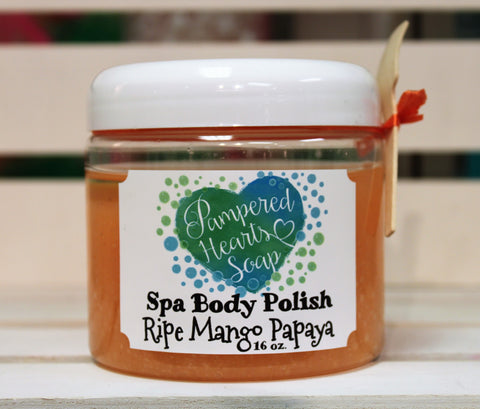 Clear 16 ounce container with white lid, a small wooden scoop and orange ribbon. Contains Ripe Mango Papaya scented body scrub, which is colored orange.