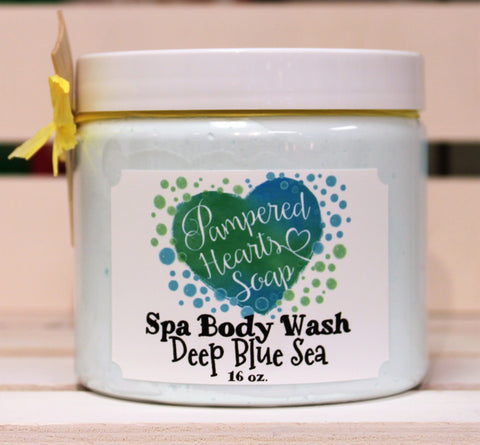 Clear 16 ounce container with white lid, a small wooden scoop and yellow ribbon. Contains Deep Blue Sea scented whipped body wash, which is colored light blue. 