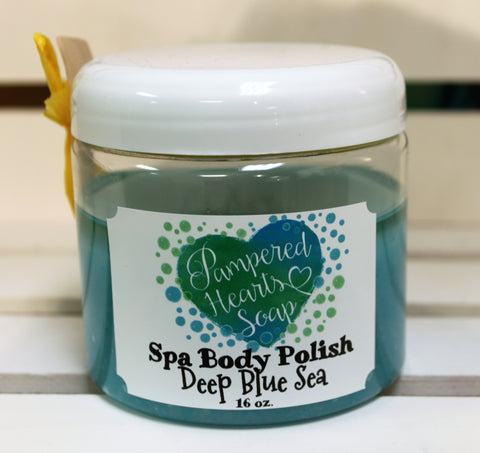 Clear 16 ounce container with white lid, a small wooden scoop and yellow ribbon. Contains Deep Blue Sea scented body scrub, which is colored blue. 