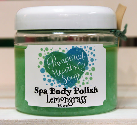 Clear 16 ounce container with white lid, a small wooden scoop and green ribbon. Contains Lemongrass scented body scrub, which is colored green.